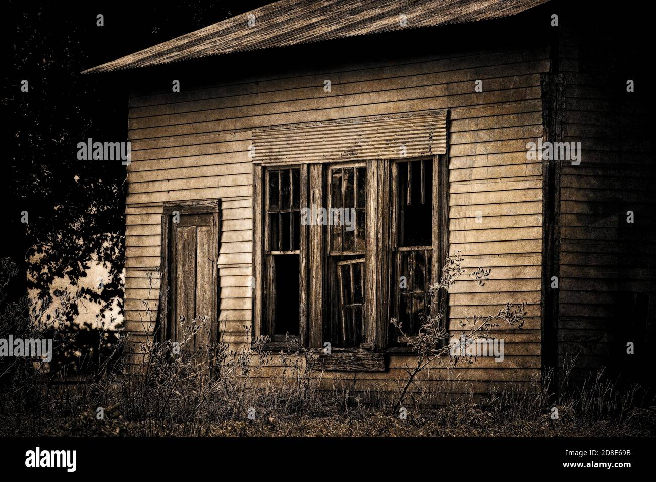 Vue latérale d'une ferme abandonnée avec trois fenêtres cassées et une porte. Photographié sur les rods arrière du Texas Hill Country. Banque D'Images