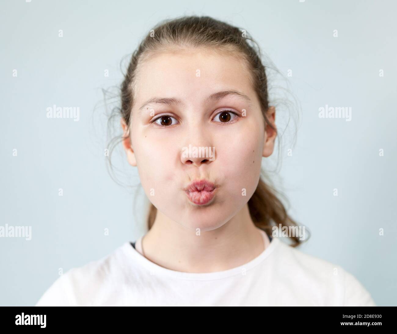 Avant-jeune fille fait un baiser avec des lèvres, regardant l'appareil photo, portrait sur fond, série d'émotions Banque D'Images