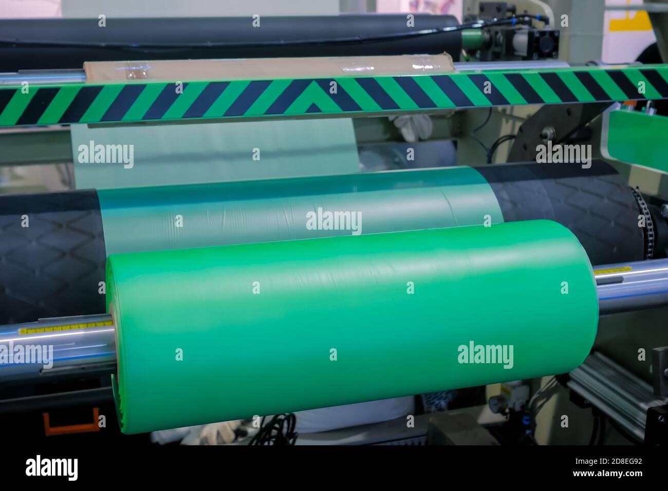 Partie de la machine automatique de fabrication de sacs en plastique - rouleau mobile avec film vert en polyéthylène plat à l'exposition, salon. Fabrication, recyclage Banque D'Images