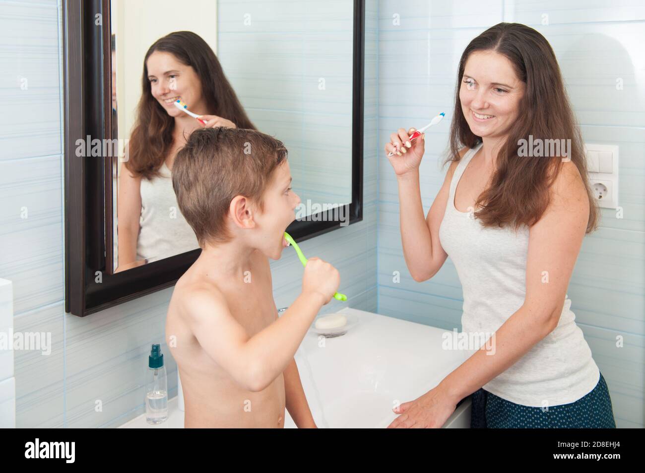 une famille heureuse et en bonne santé ensemble mère souriante femme et garçon enfant brossez-vous les dents dans la salle de bains en utilisant une brosse à dents qui se regarde l'une Banque D'Images