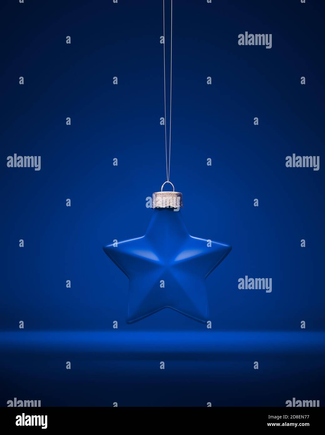 Décoration de Noël bleu mat. Boule en forme d'étoile à cinq pointes accrochée à une corde sur fond bleu roi. Décoration de Noël, atmosphère festive conce Banque D'Images