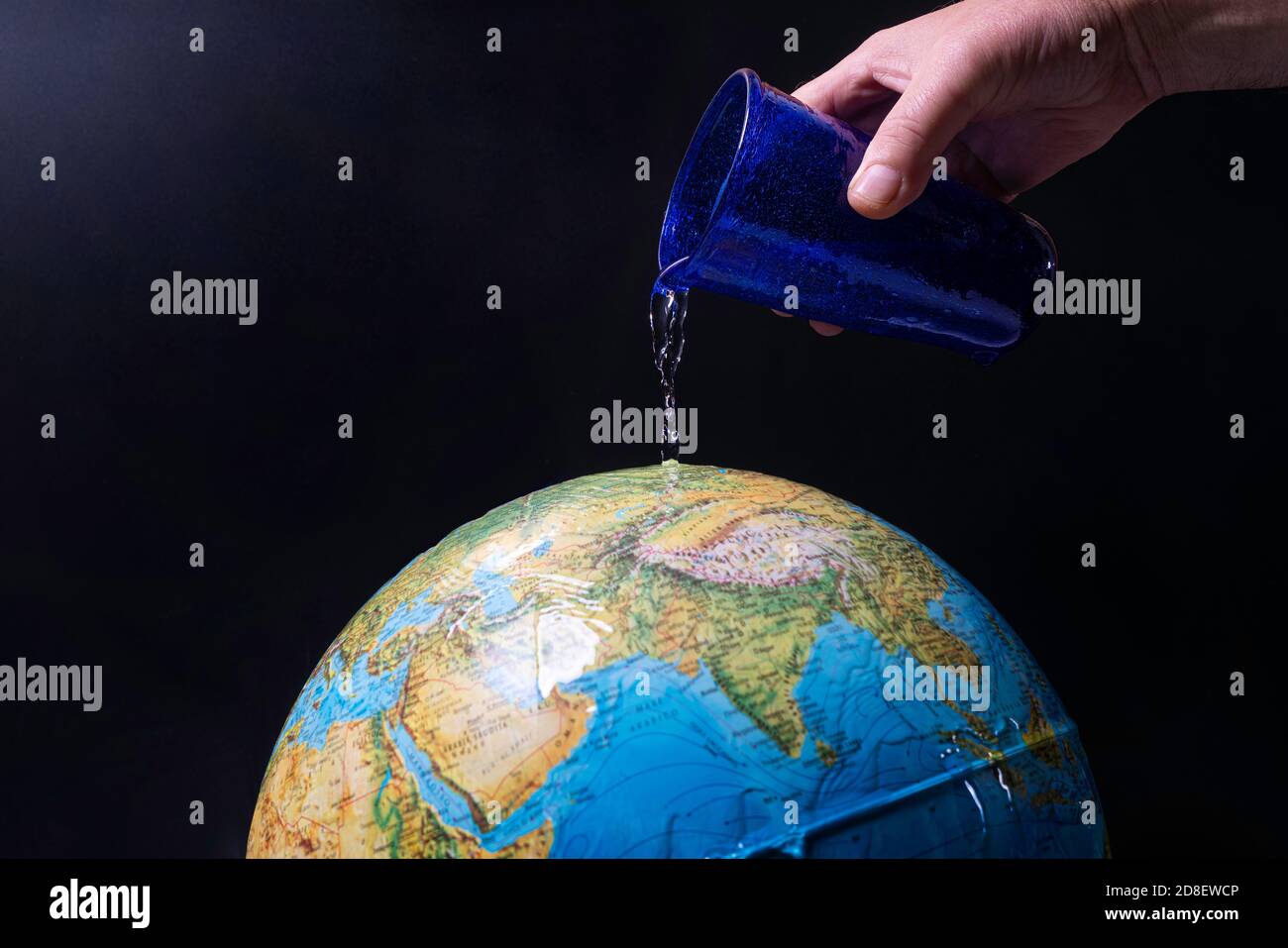 un verre d'eau versé sur le globe assoiffé de la masse Banque D'Images