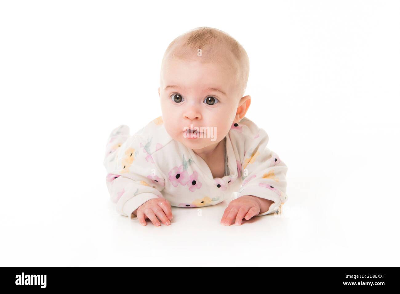 jeune fille de 3 mois couchée au sol isolée sur un fond blanc. Banque D'Images