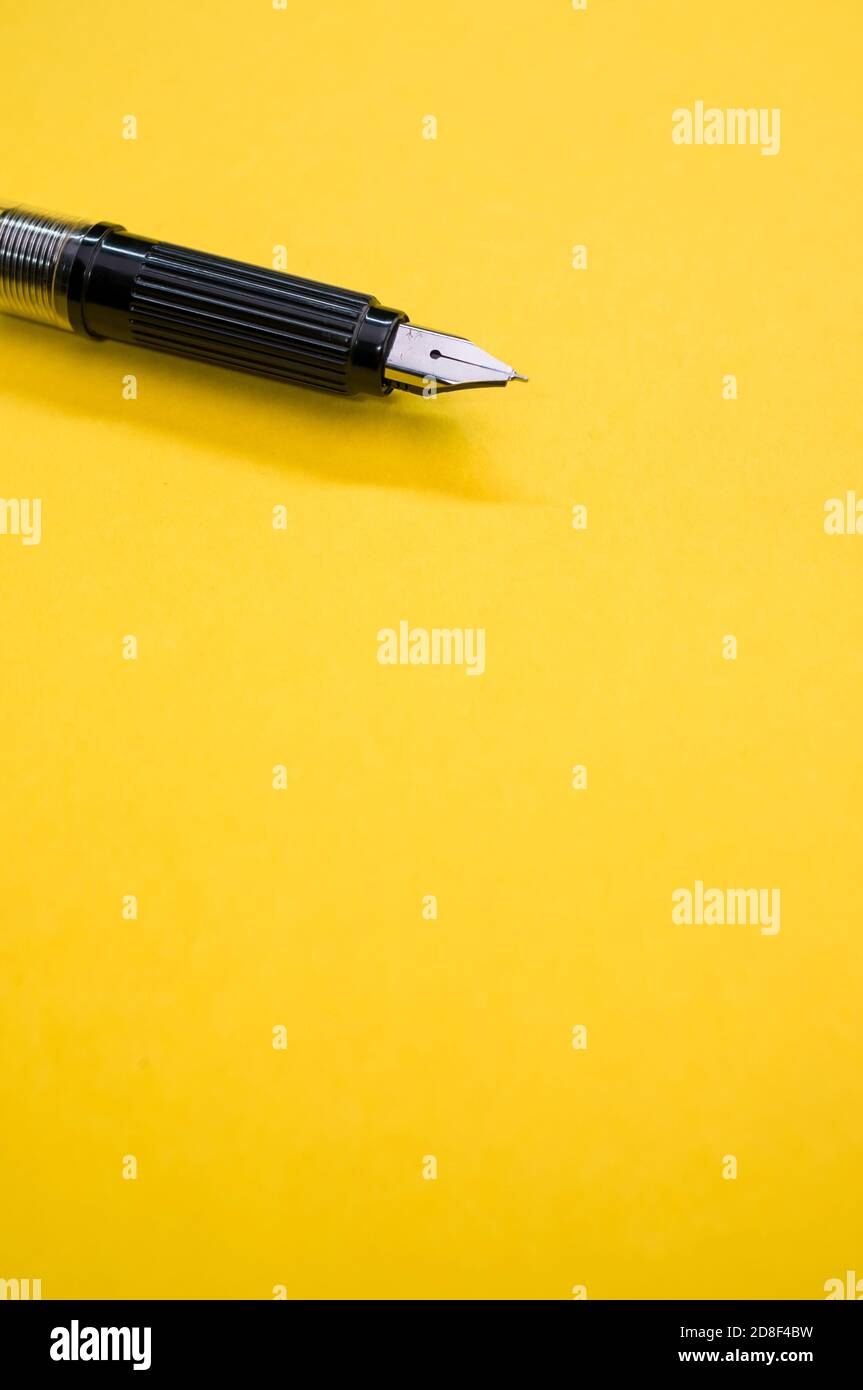 Gros plan d'un stylo plume sur la surface jaune - espace pour le texte Banque D'Images