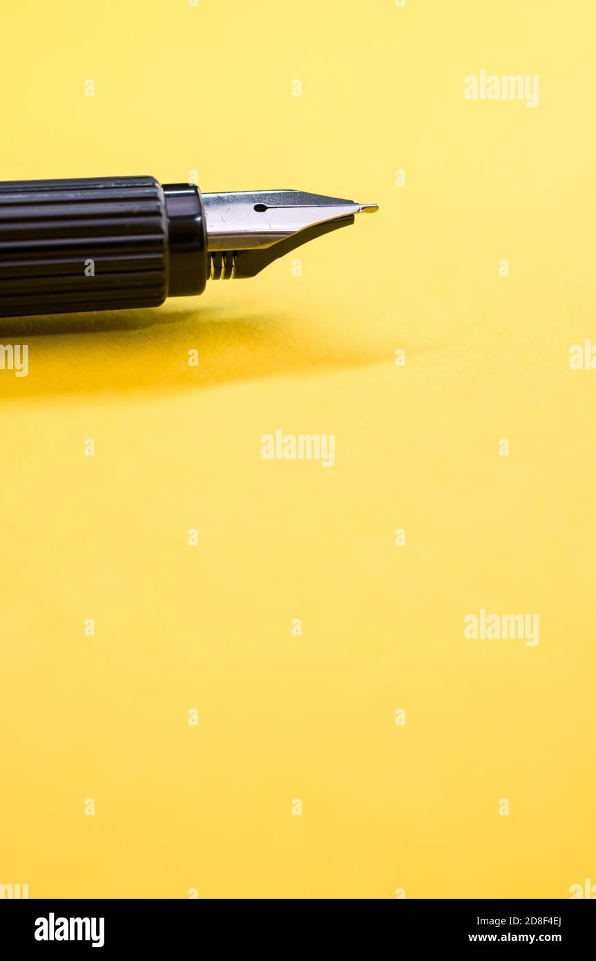 Gros plan d'un stylo plume sur la surface jaune - espace pour le texte Banque D'Images