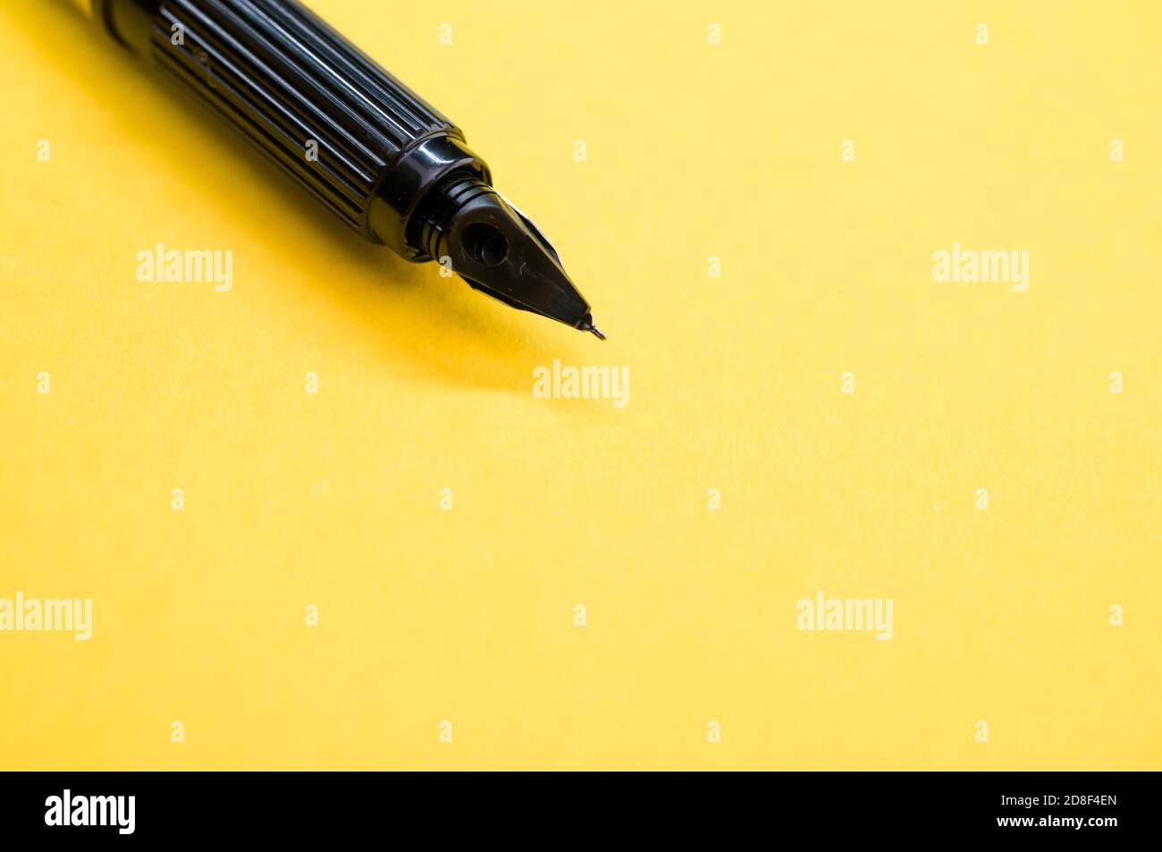 Gros plan d'un stylo plume sur la surface jaune - espace pour le texte Banque D'Images