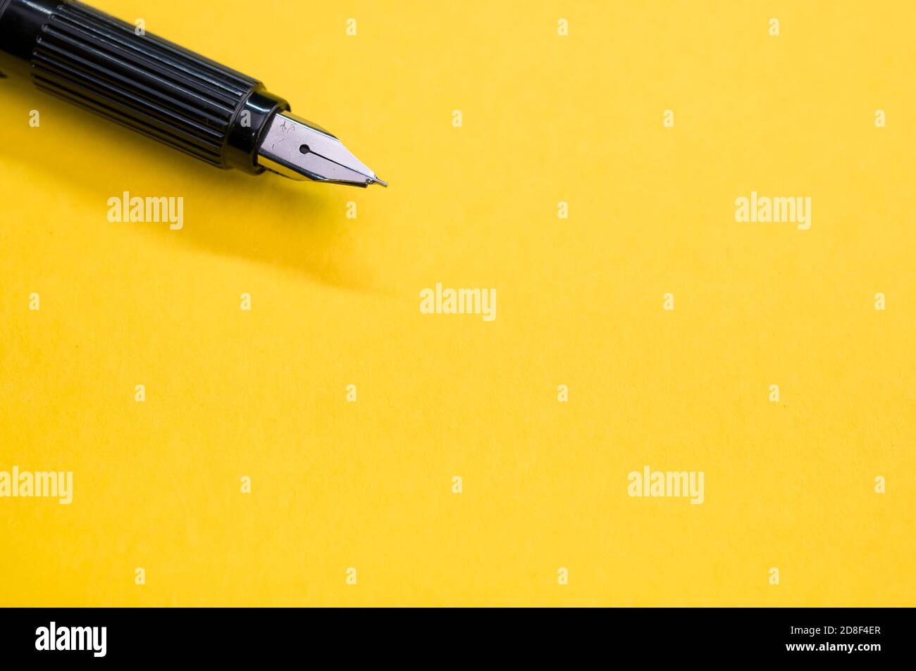 Gros plan d'un stylo plume sur la surface jaune - espace pour le texte Banque D'Images