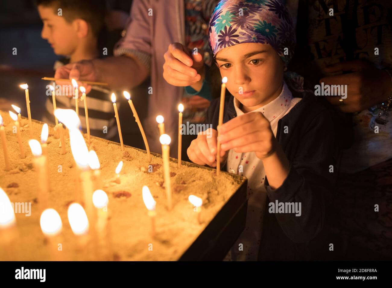 Une fille allume une bougie dans la prière à l'église Jvari, l'un des sites les plus saints de Géorgie à Mtskheta, Géorgie, Caucase, Europe. Banque D'Images