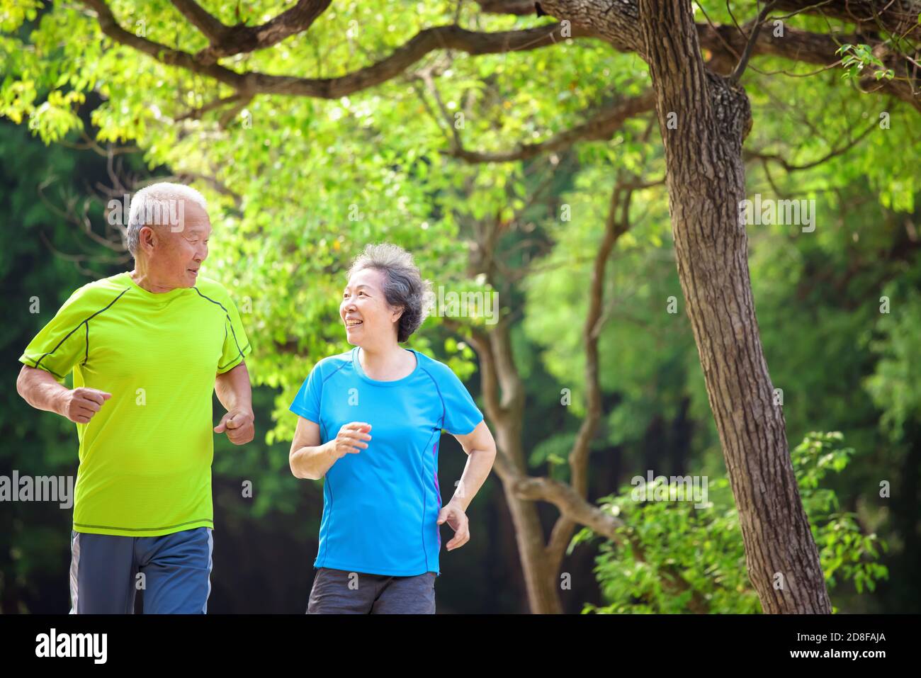 Bon couple Senior jogging dans le parc naturel Banque D'Images