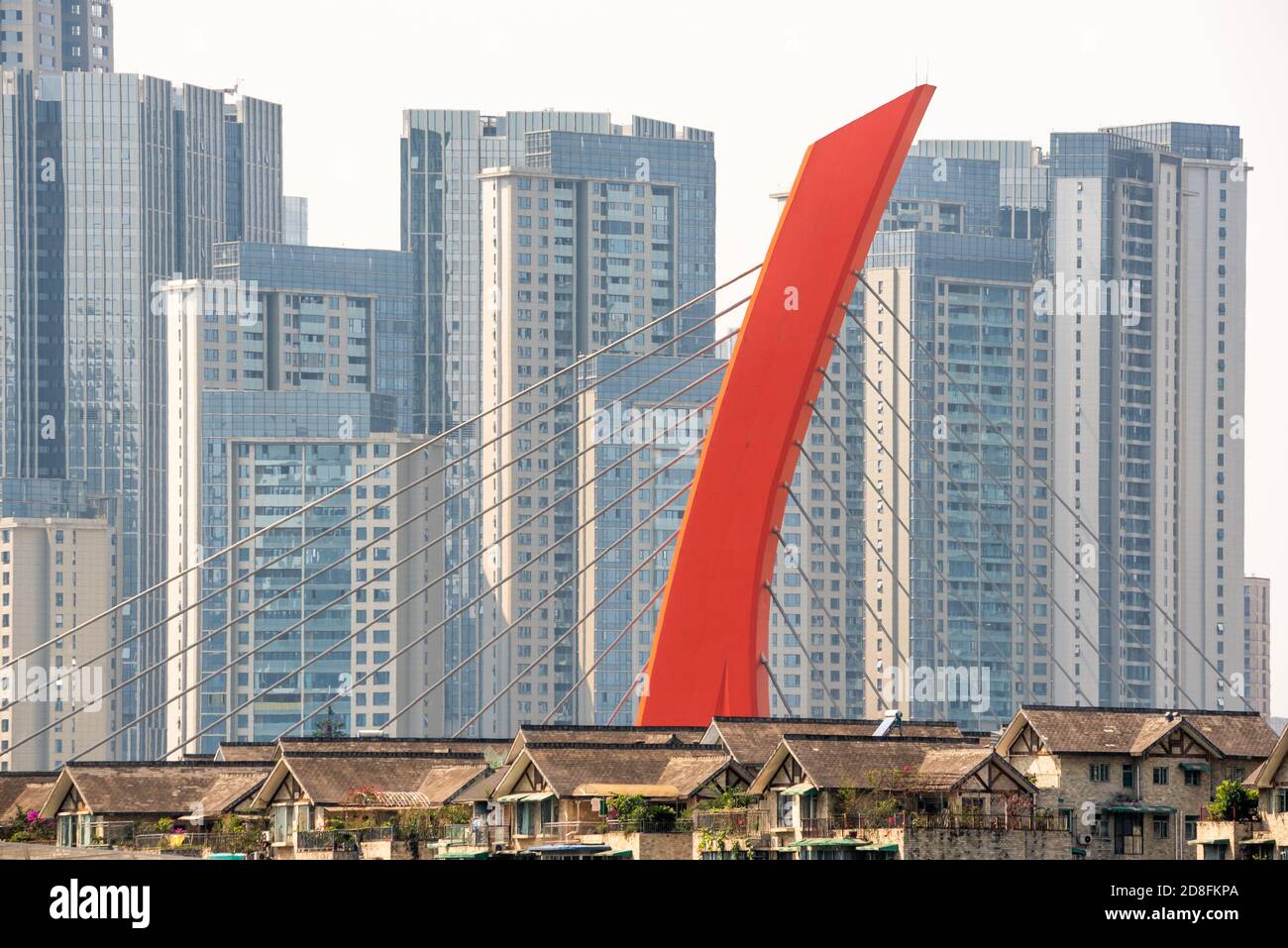 Chengdu, province du Sichuan, Chine - 2 juillet 2020 : Pont en câble rouge avec des maisons en premier plan et des gratte-ciels en arrière-plan dans la partie sud de la ville. Banque D'Images