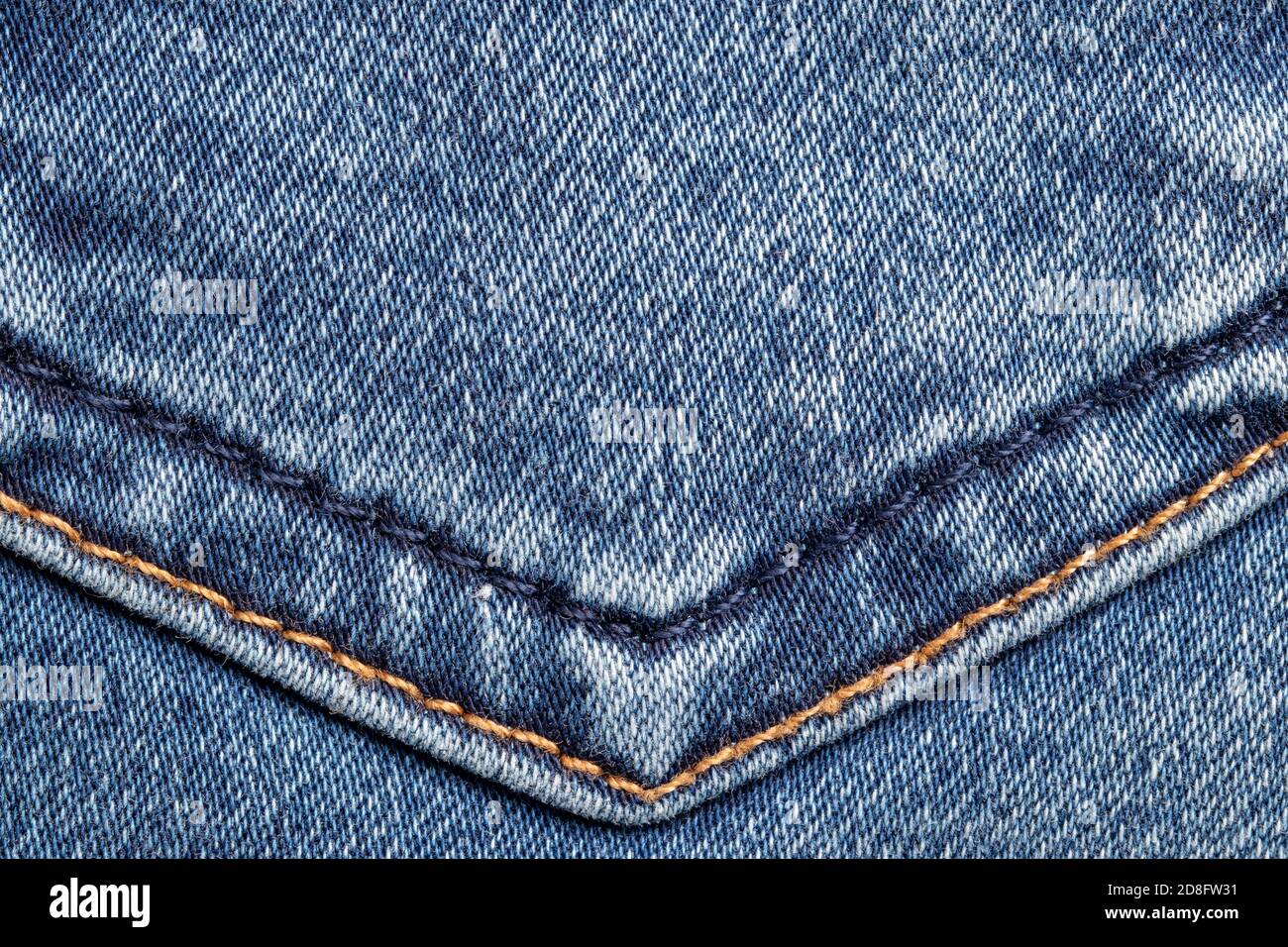 Texture d'arrière-plan du denim. Gros plan sur les détails d'une surface jean bleu clair avec double couture dorée et bleue. Macro. Vue de dessus. Beaut Banque D'Images