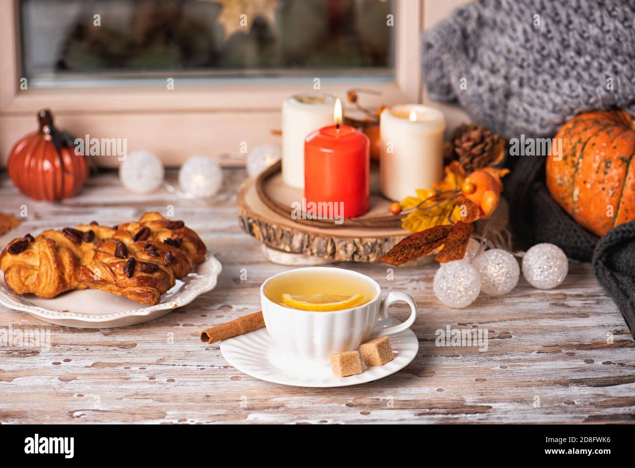 Thé chaud et pâtisseries avec pecan sur le seuil de la fenêtre, temps pluvieux dehors. Décoration automnale et bougies. Concept de maison confortable. Banque D'Images