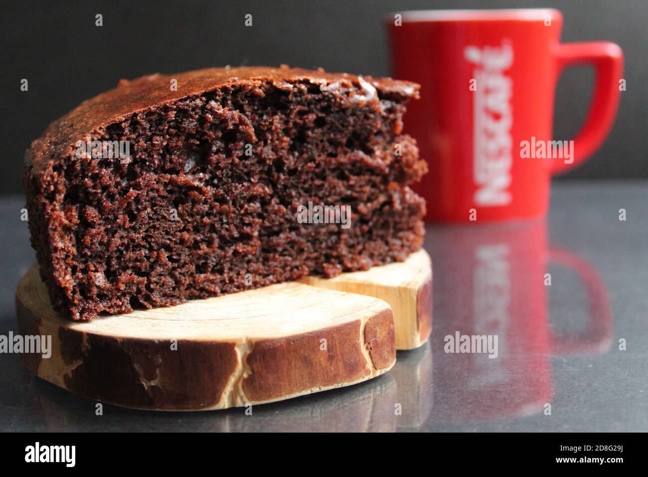 tarte au chocolat et au brownie sur un meuble en bois en rondins à l'arrière En arrière-plan est une tasse rouge une tasse de thé café lait sur fond noir avec une copie espace Banque D'Images