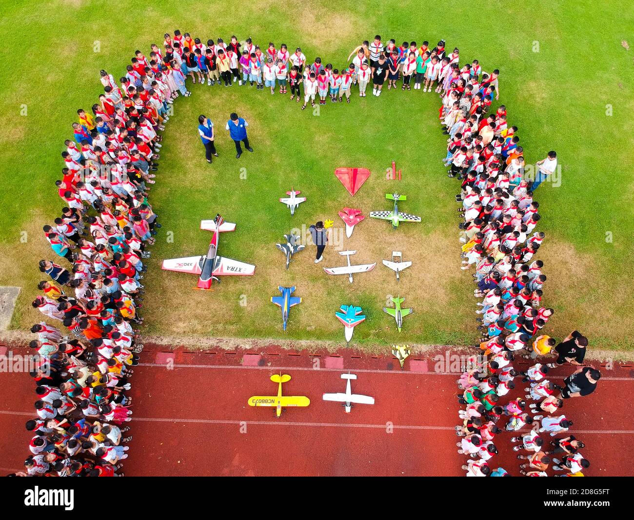 Guidés par les enseignants, les étudiants qui retournent sur le campus au début du nouveau semestre, testent leurs modèles d'avions dans le terrain de jeu d'une école primaire locale, Rug Banque D'Images