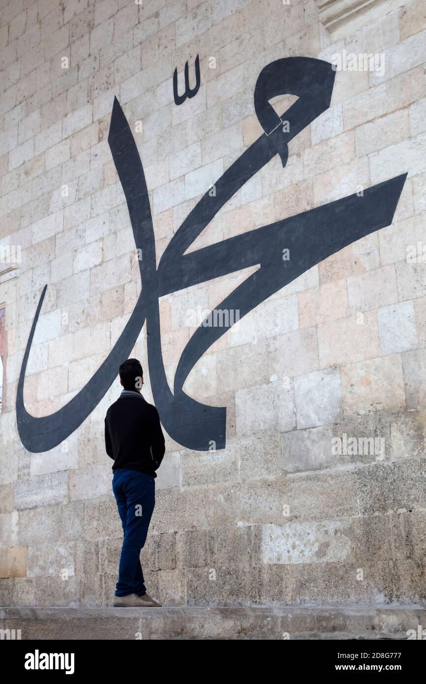 Jeune homme regardant la calligraphie arabe signifiant « Prophète Muhammad » Sur le mur de la vieille mosquée d'Edirne Banque D'Images