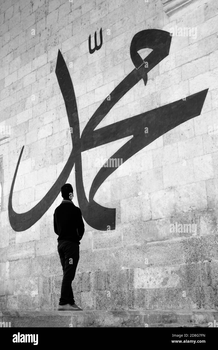 Jeune homme regardant la calligraphie arabe signifiant « Prophète Muhammad » Sur le mur de la vieille mosquée d'Edirne Banque D'Images