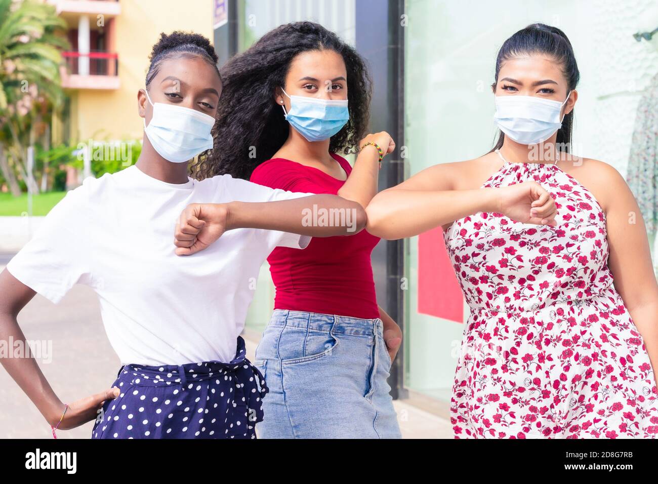 Les jeunes filles portant un masque facial faisant une nouvelle distanciation sociale saluent avec des coudes pour prévenir la propagation du virus corona. Covid 19 et concept d'amitié Banque D'Images