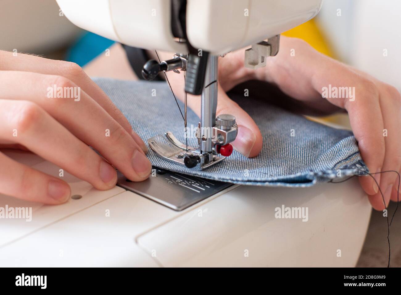 Gros plan de la couture sur une machine à coudre, les mains dirigent le denim. Le concept de créativité, passe-temps Banque D'Images