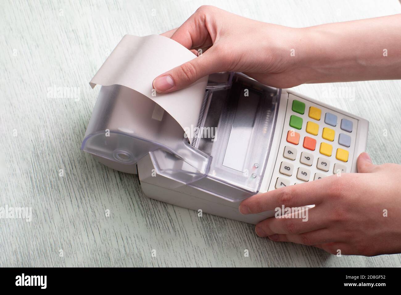 Les mains d'une jeune femme déchirant un chèque d'une caisse après avoir acheté un produit, en entrant une remise sur un marché Banque D'Images