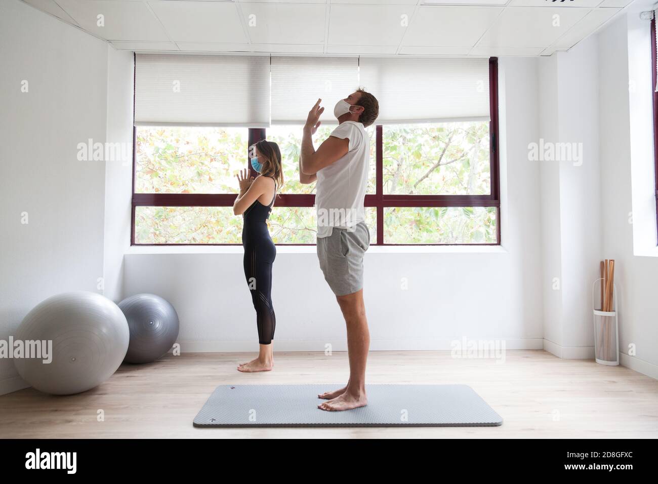Yogi débutant et son entraîneur pratiquant le yoga portant un masque de protection Banque D'Images