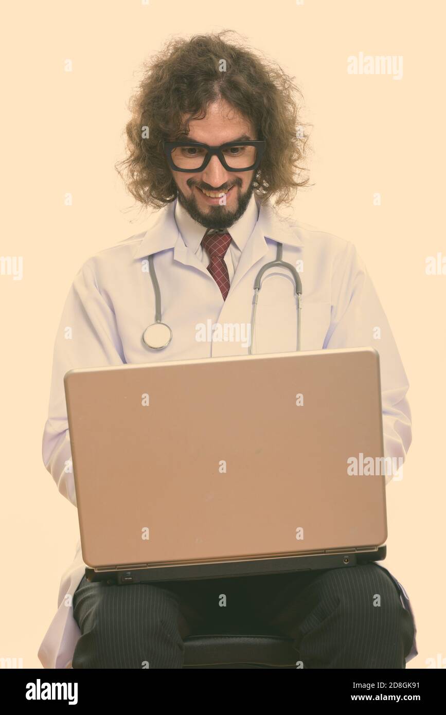 Studio shot of happy man doctor smiling while using laptop Banque D'Images