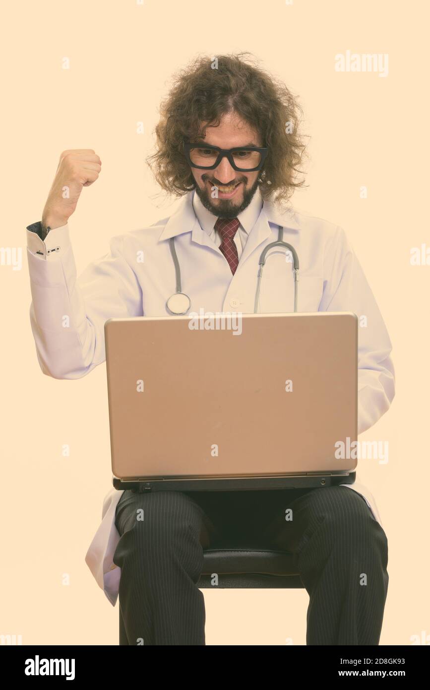Studio shot of happy man doctor smiling while using laptop avec fist soulevées Banque D'Images