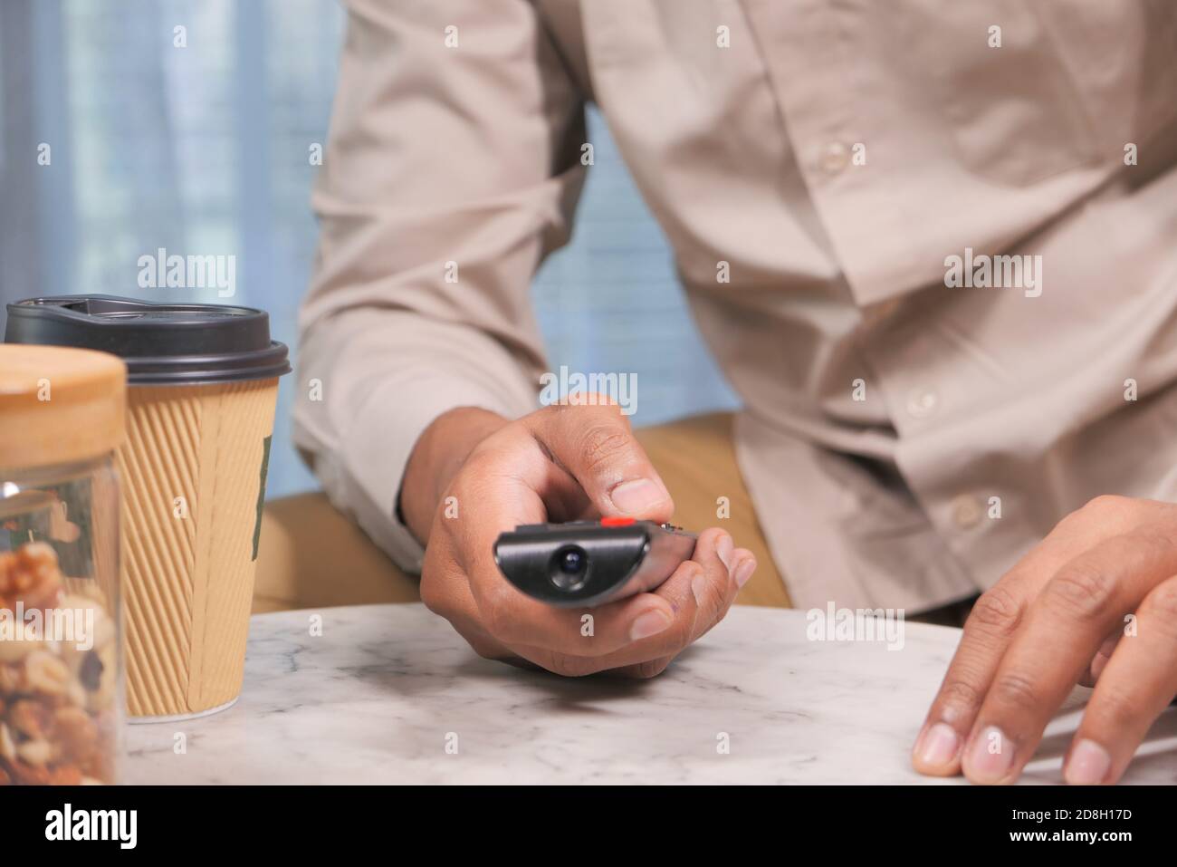 jeune homme assis sur un canapé à l'aide de la télécommande du téléviseur Banque D'Images