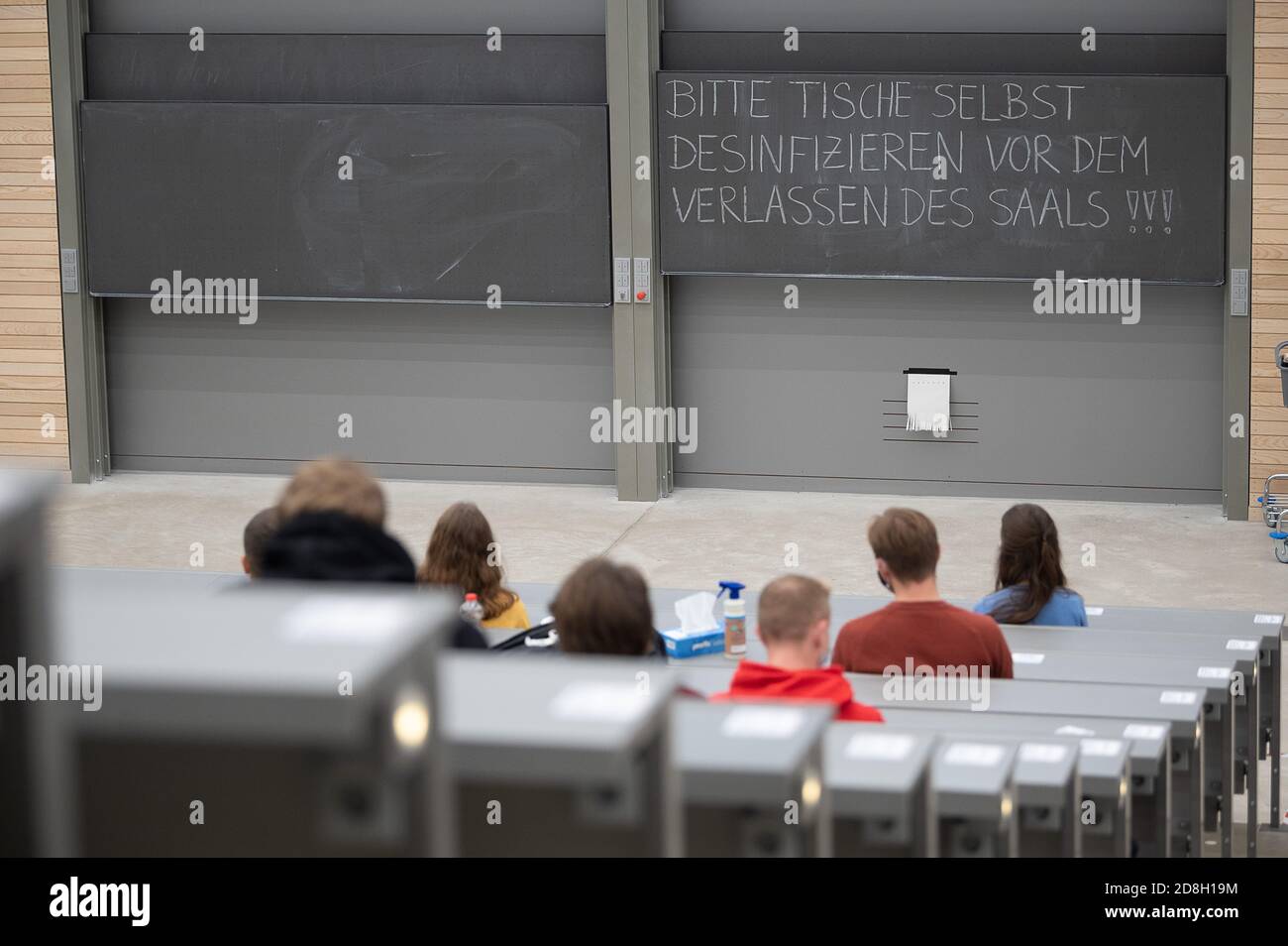 29 octobre 2020, Baden-Wuerttemberg, Stuttgart: Les étudiants portant des masques buccaux et nasaux sont assis devant un tableau noir lors de l'événement de bienvenue pour les étudiants du premier semestre à l'université de Hohenheim qui se lit comme suit: « Veuillez désinfecter les tables vous-même avant de quitter le hall ». Le semestre d'hiver 2020/2021 commence à Baden-Württemberg le 2 novembre dans des conditions d'hygiène plus strictes en raison de la pandémie du coronavirus. Photo: Sebastian Gollnow/dpa Banque D'Images