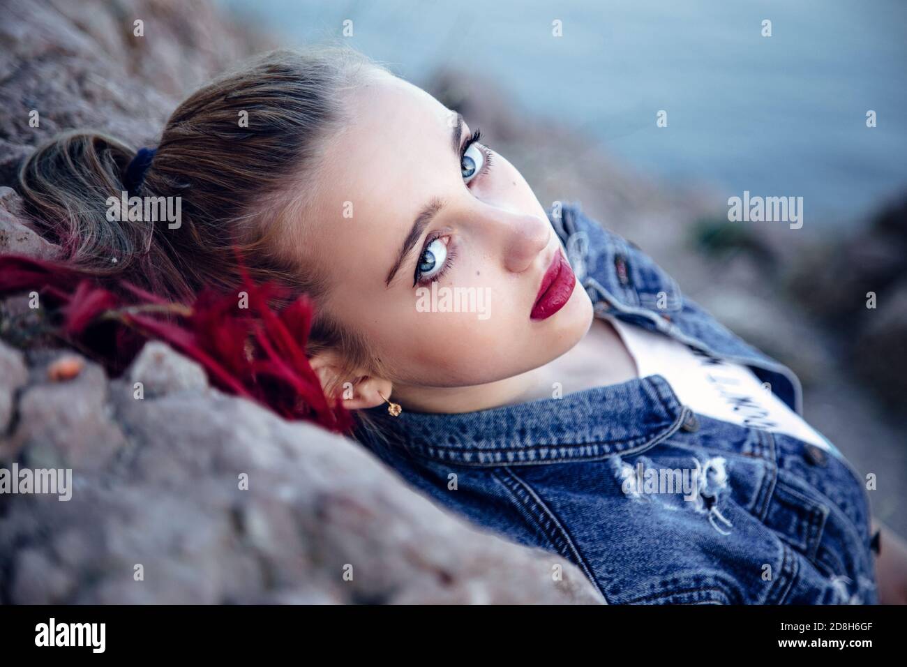 Belle jeune fille avec des yeux bleus et des lèvres et cheveux brillants. Arrière-plan flou à des fins artistiques. Banque D'Images