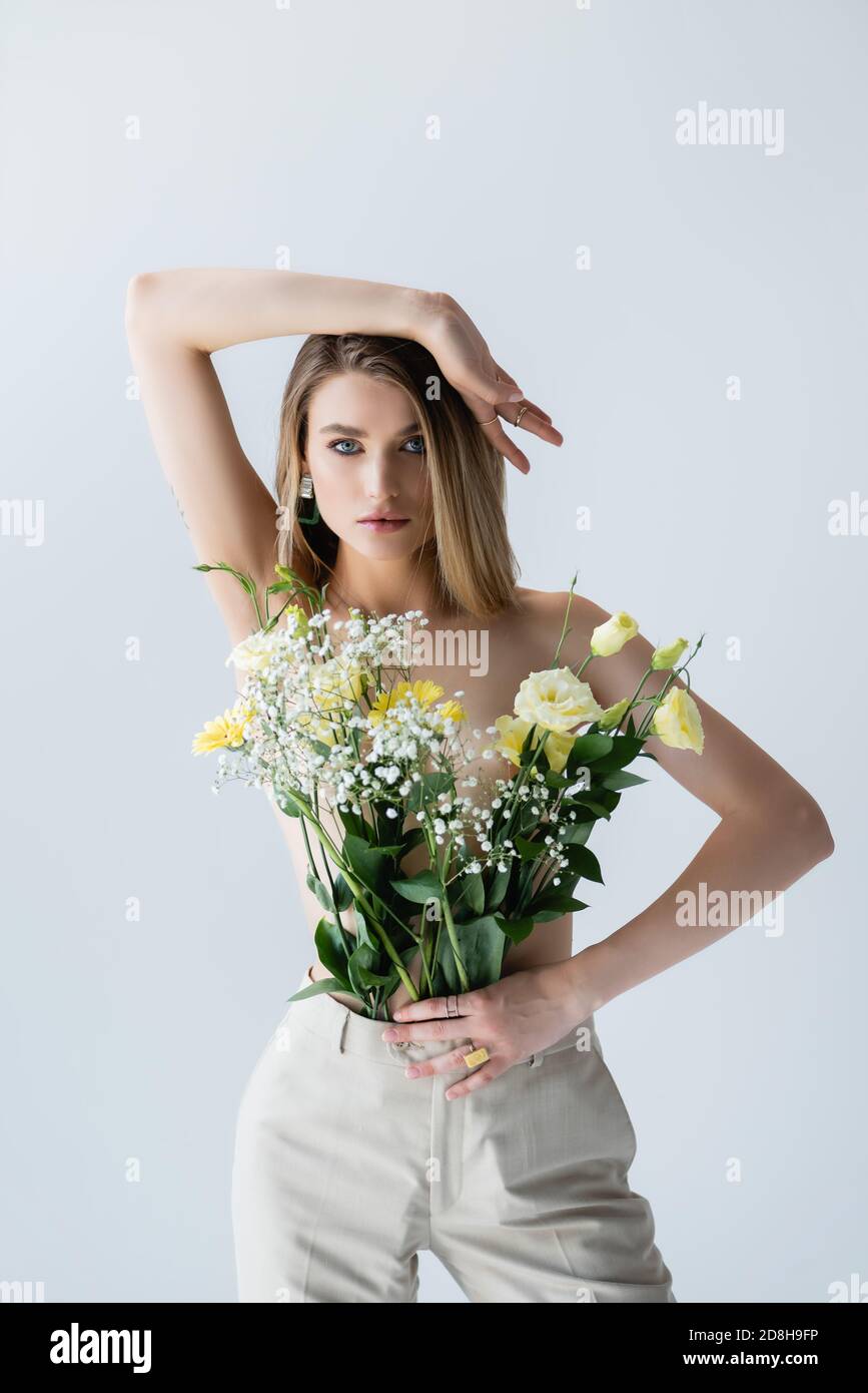 jeune modèle avec bouquet de fleurs dans le pantalon posé sur blanc Banque D'Images