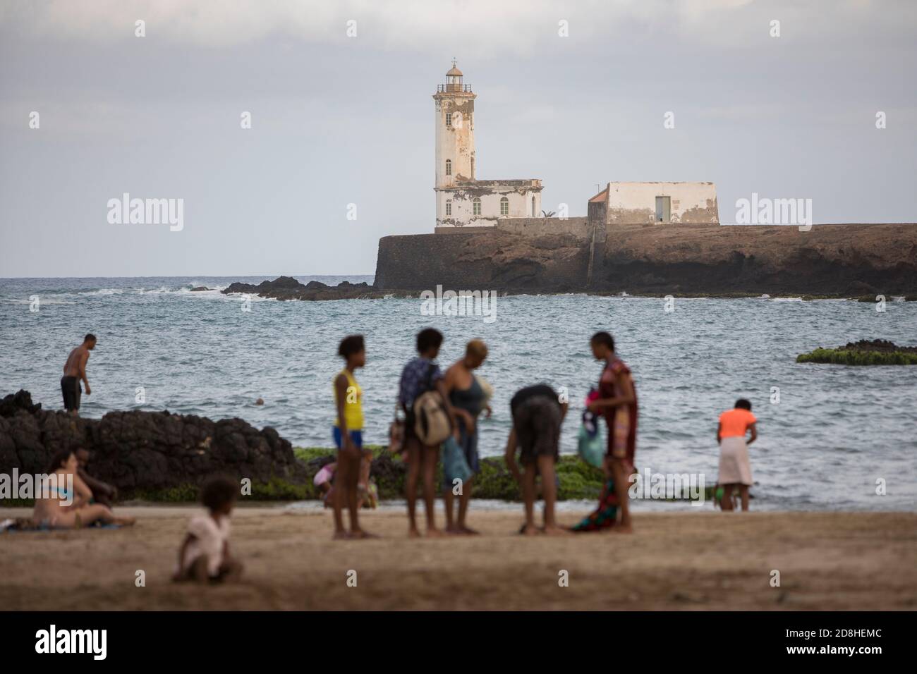 Les amateurs de plage nagent près d'un phare de l'îlot Santa Maria à Praia, Santiago, Cap-Vert. Banque D'Images
