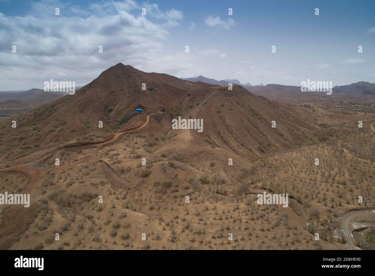 Un réservoir d'eau peint en bleu clair et une station de pompage peuvent être vus au sommet d'une colline sèche et stérile sur l'île de Maio au Cap-Vert. Banque D'Images