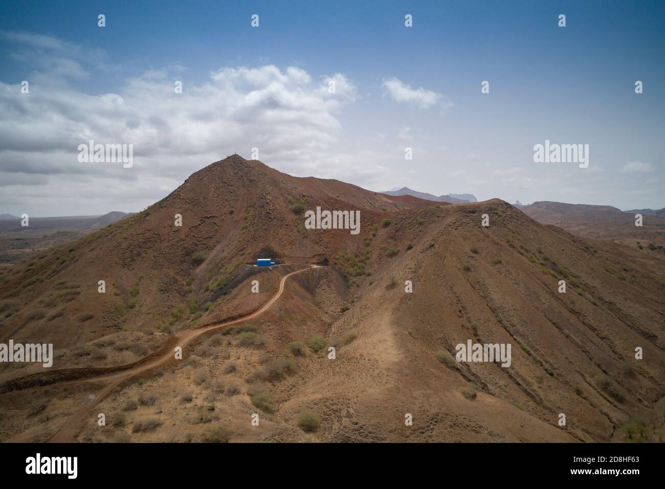 Un réservoir d'eau peint en bleu clair et une station de pompage peuvent être vus au sommet d'une colline sèche et stérile sur l'île de Maio au Cap-Vert. Banque D'Images