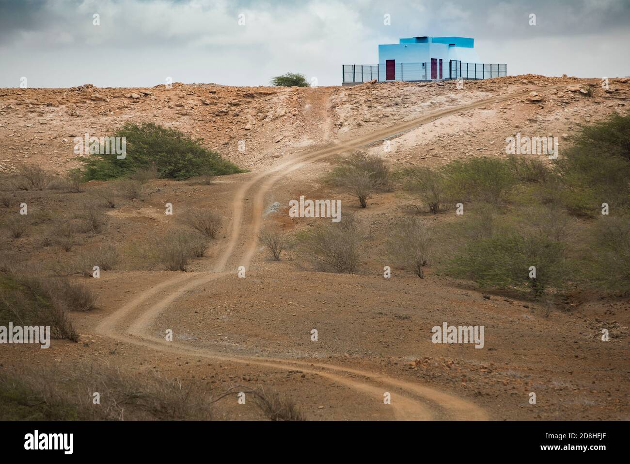 Un réservoir d'eau peint en bleu clair et une station de pompage peuvent être vus au sommet d'une colline sèche et stérile sur l'île de Maio au Cap-Vert. Banque D'Images