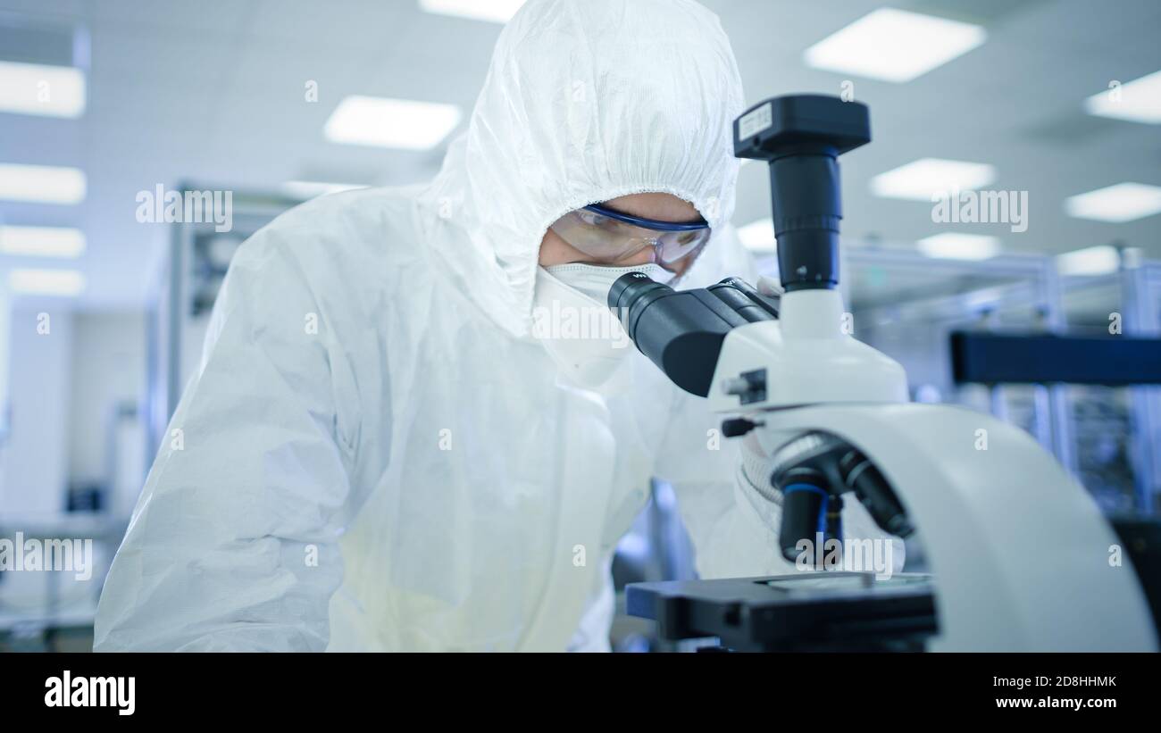 En laboratoire scientifique dans les vêtements de protection faire de la recherche utilise le microscope. Manufacture moderne produisant des semiconducteurs et des articles pharmaceutiques. Banque D'Images