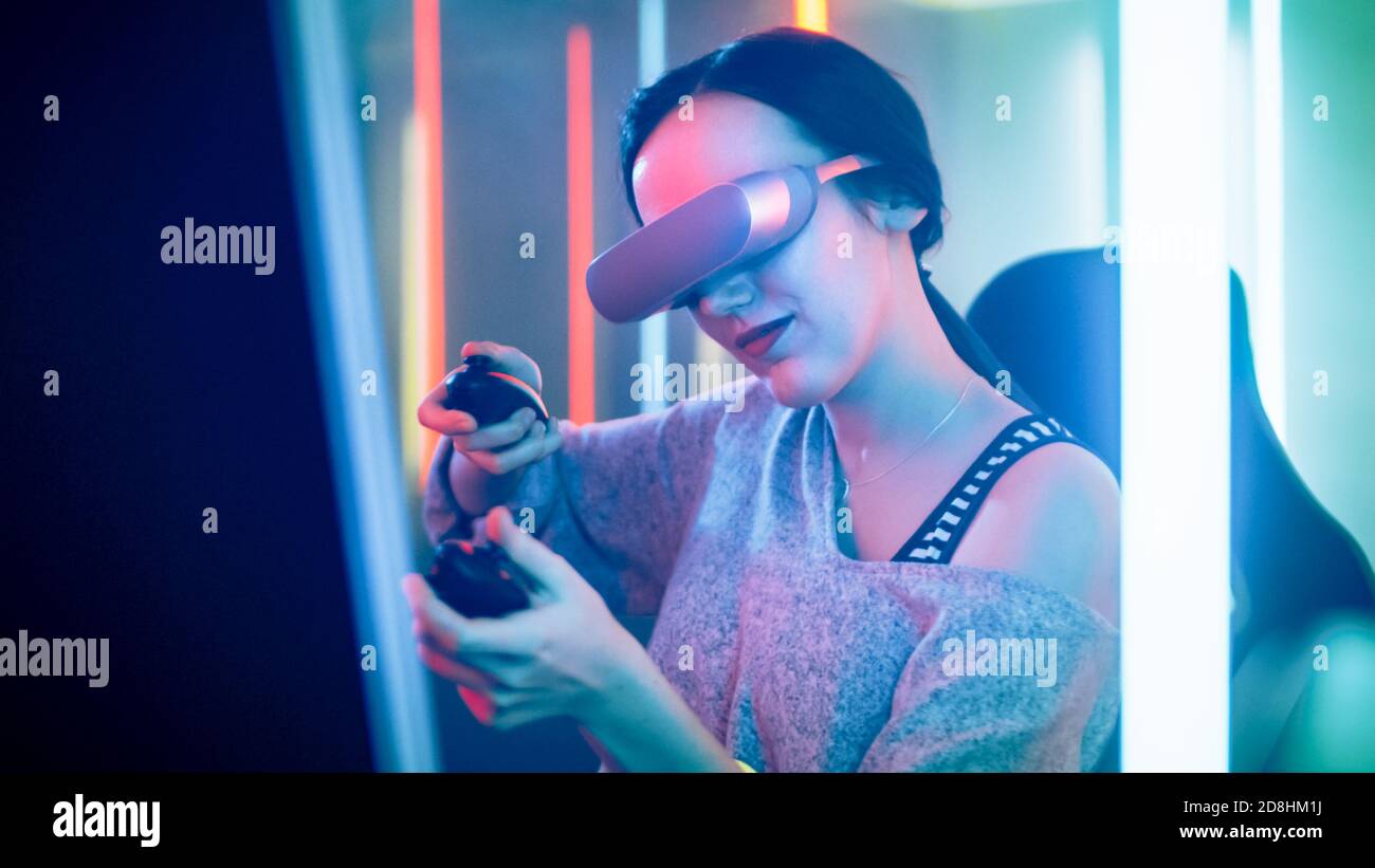 Pro Gamer Girl Wearing Virtual Reality Headset joue le tournage de jeu vidéo en ligne avec des manettes de commande. Couleurs fluo rétro dans la chambre. Banque D'Images