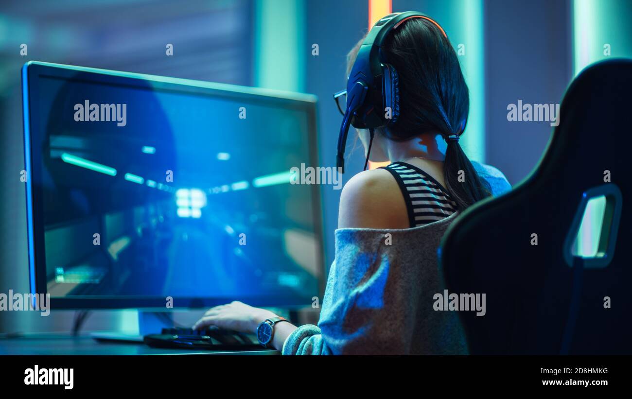 Photo de la belle fille de joueur professionnel jouant dans le jeu vidéo FPS sur son ordinateur personnel, décontracté mignon Geek portant des lunettes et un casque. Salle Neon Banque D'Images