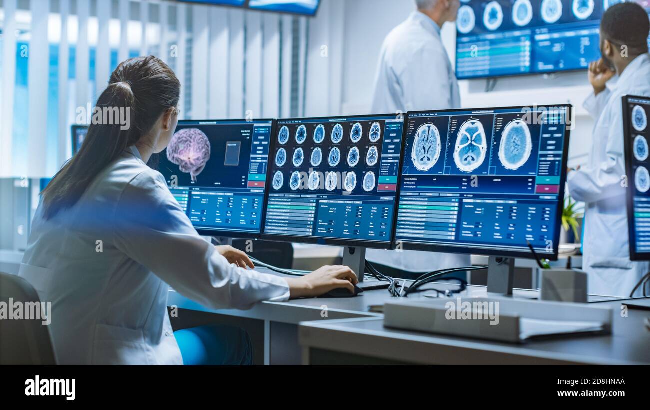 Une équipe de scientifiques professionnels travaille au laboratoire de recherche sur le cerveau. Neurologues neuroscientifiques entourés de moniteurs présentant des examens CT et IRM Banque D'Images