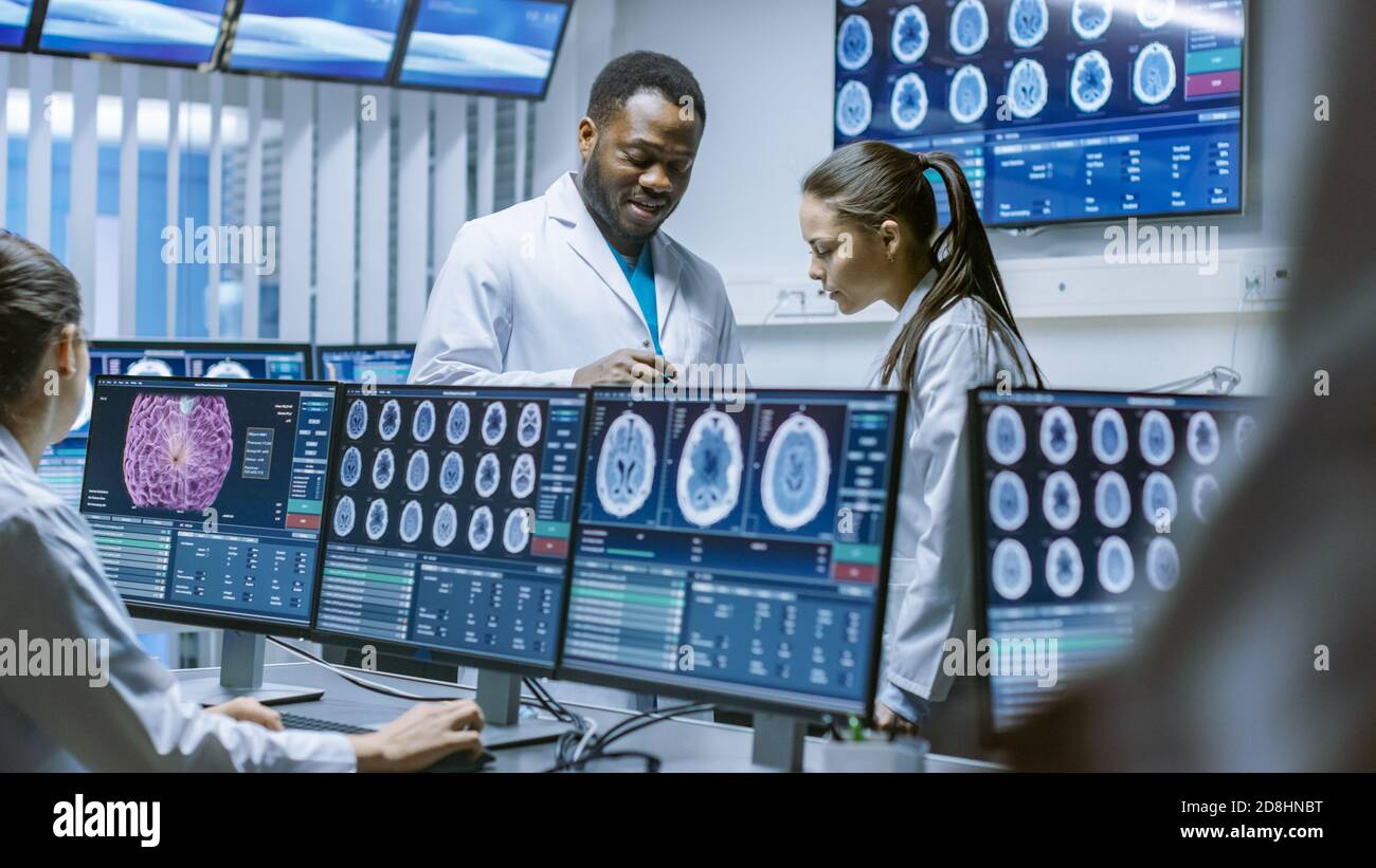 Les scientifiques médicaux du laboratoire de recherche sur le cerveau discutent des progrès réalisés dans le cadre du projet de neurophysiologie. Neuroscientifiques entourés d'écrans montrant Banque D'Images