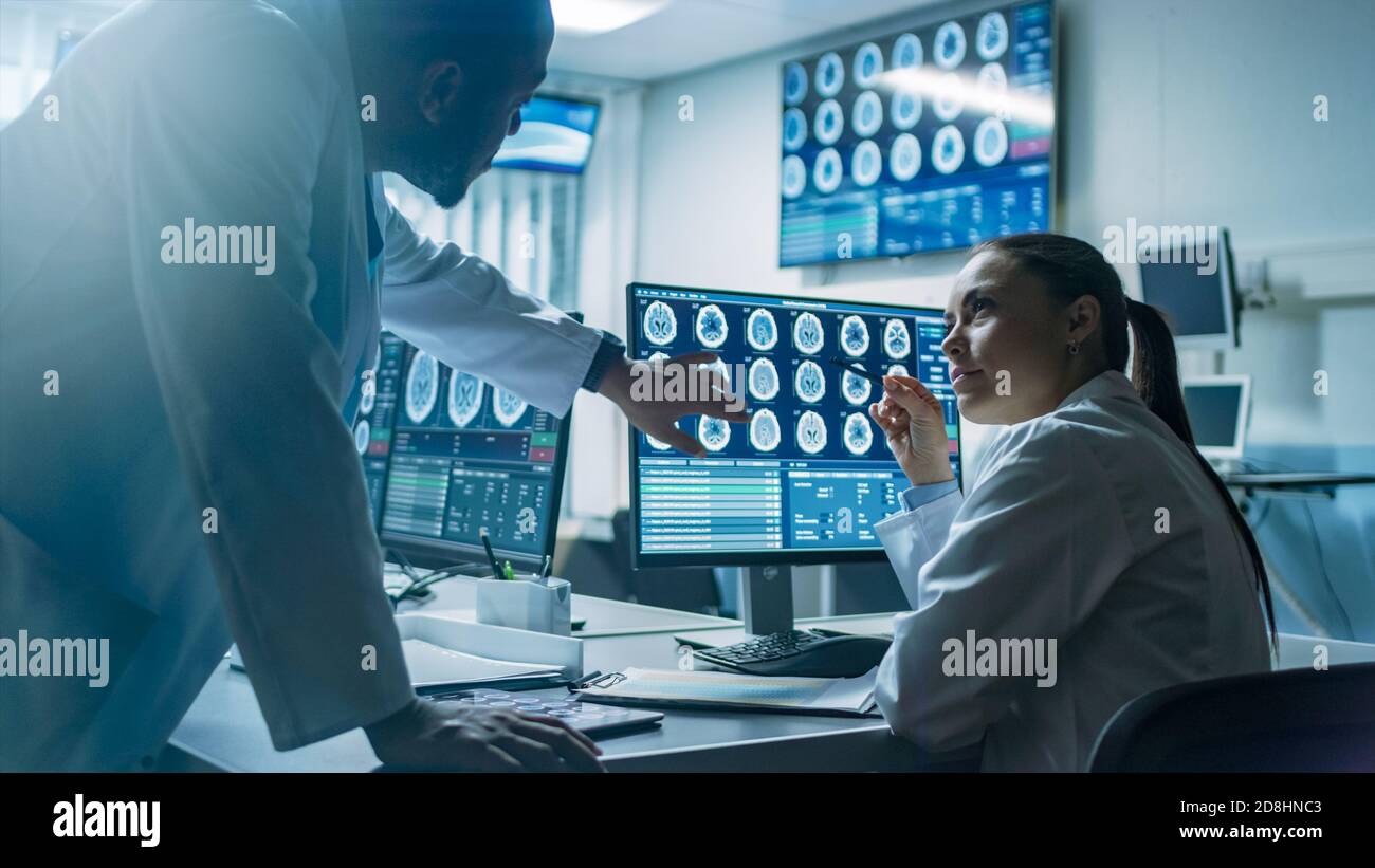 Deux scientifiques du laboratoire de recherche sur le cerveau travaillent sur un projet, en utilisant un ordinateur personnel avec des IRM montrent des anomalies cérébrales. Neuroscientifiques à Banque D'Images