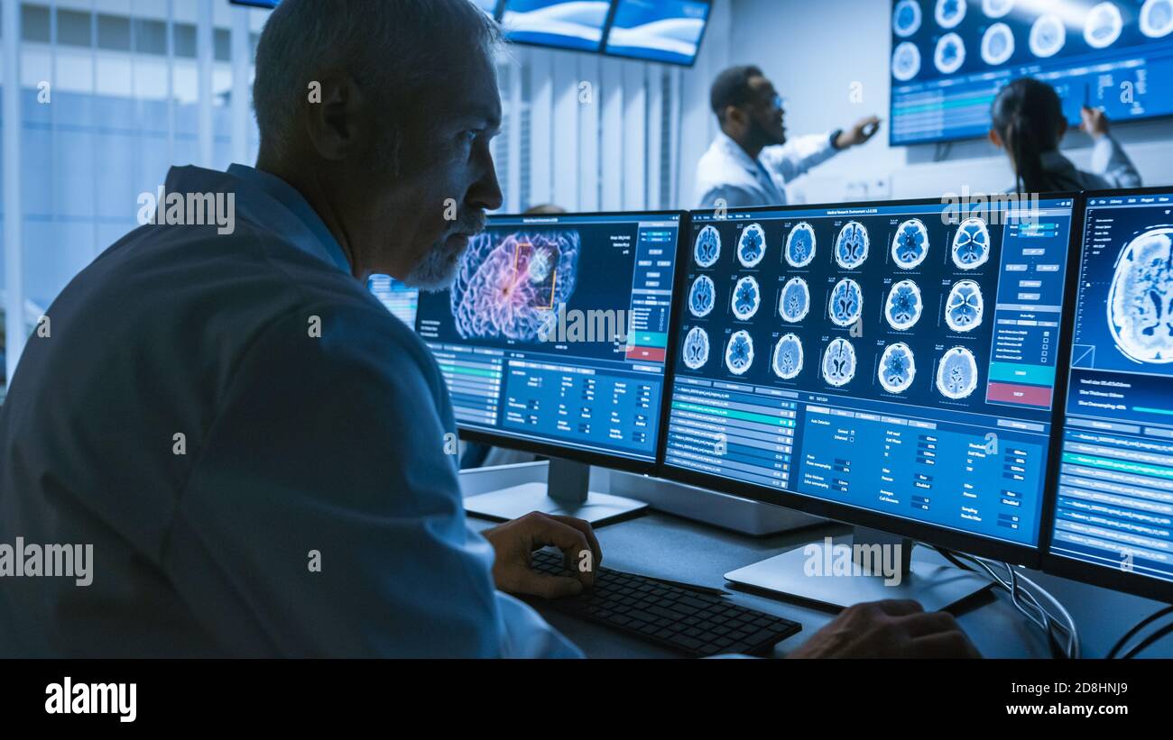 Prise de vue au-dessus de l'épaule d'un scientifique médical senior travaillant avec des images CT Brain Scan sur un ordinateur personnel en laboratoire. Neurologues en recherche Banque D'Images