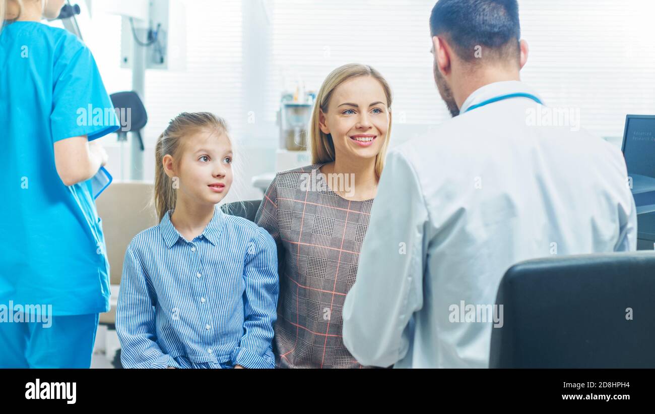 Mère avec Sweet Little Girl visite sympathique pédiatre. Le médecin leur parle après un examen approfondi. Bureau médical moderne Brightand. Banque D'Images