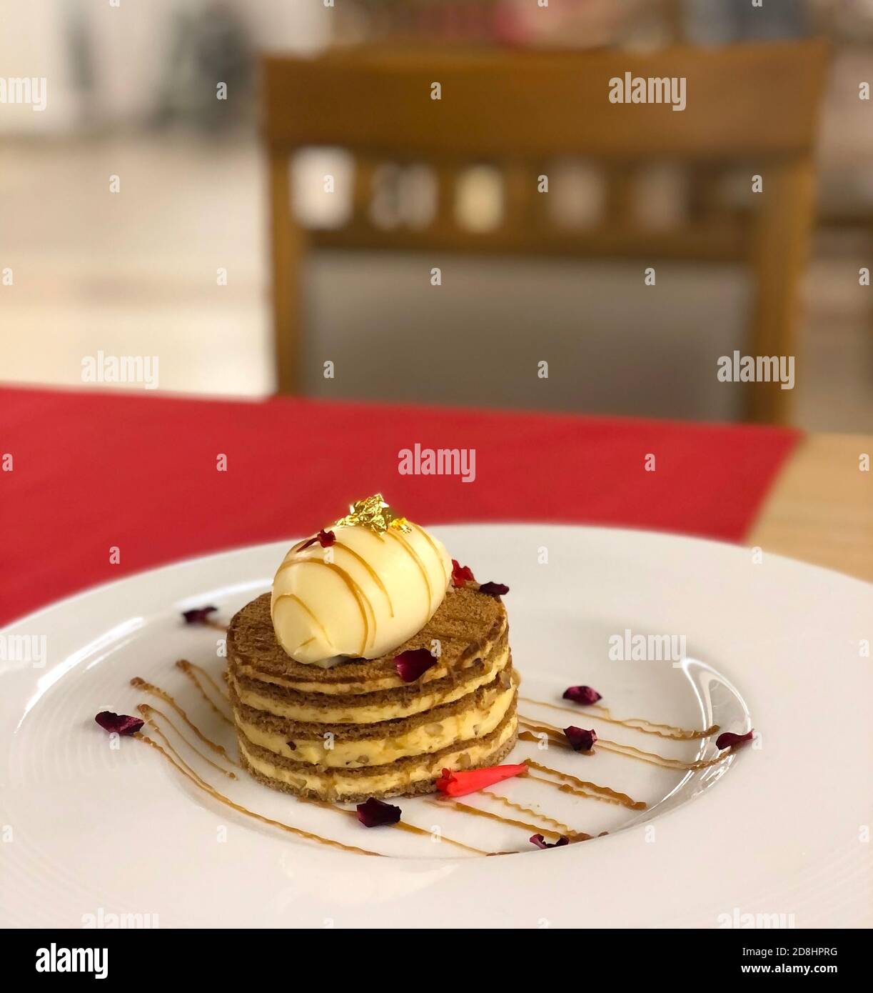 Gâteau magnifique et savoureux sur une plaque blanche décorée avec pétales de rose Banque D'Images