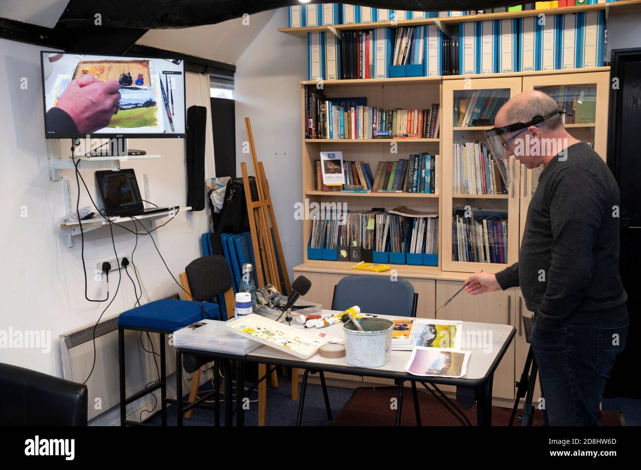 Au cours de la pandémie ou épidémie actuelle de Covid 19, un professeur d'art utilisant un écran d'ordinateur et démontrant ses techniques d'art dans une salle de classe à son art Banque D'Images