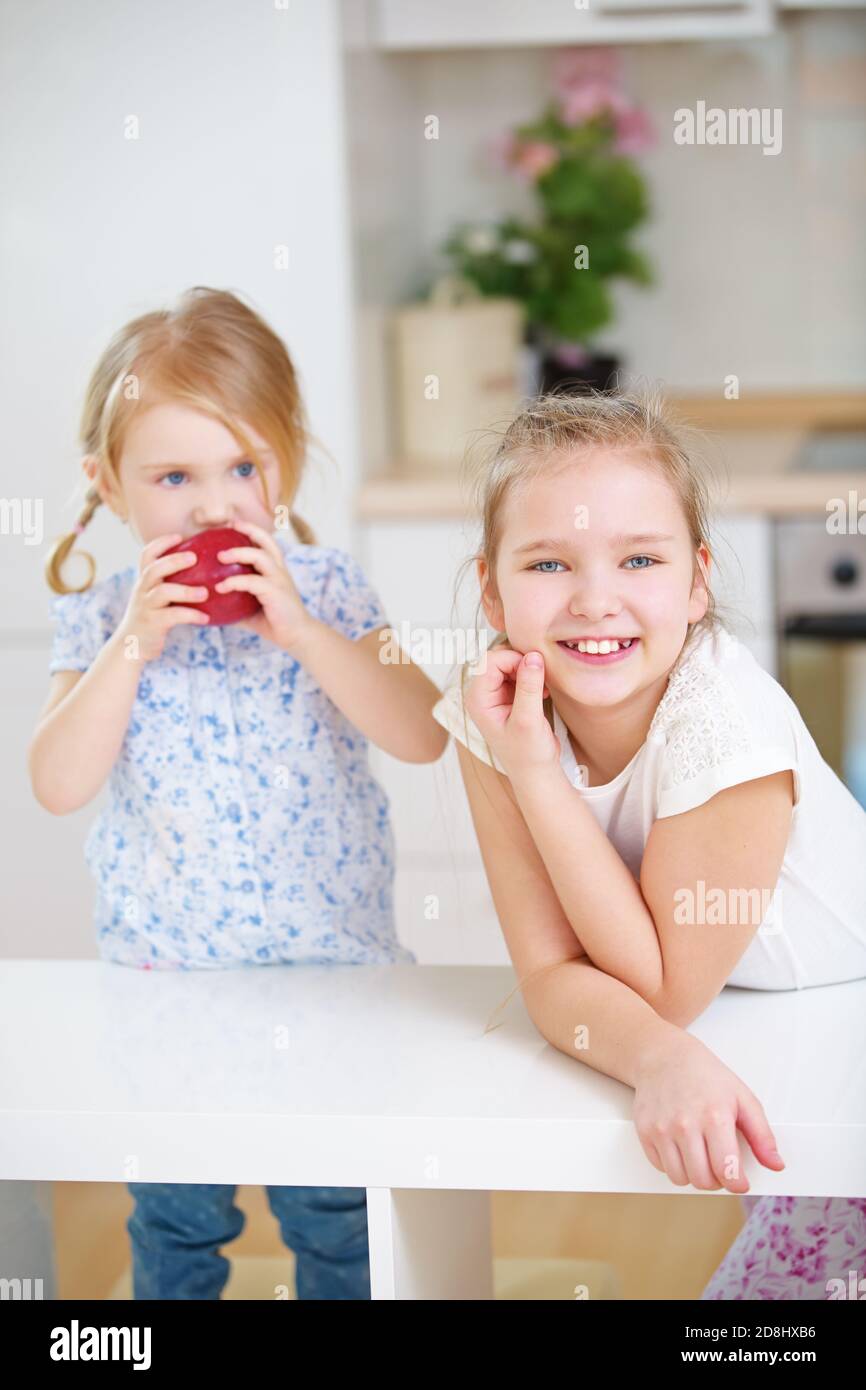 Une famille d'enfants dans la cuisine avec une pomme rouge Banque D'Images