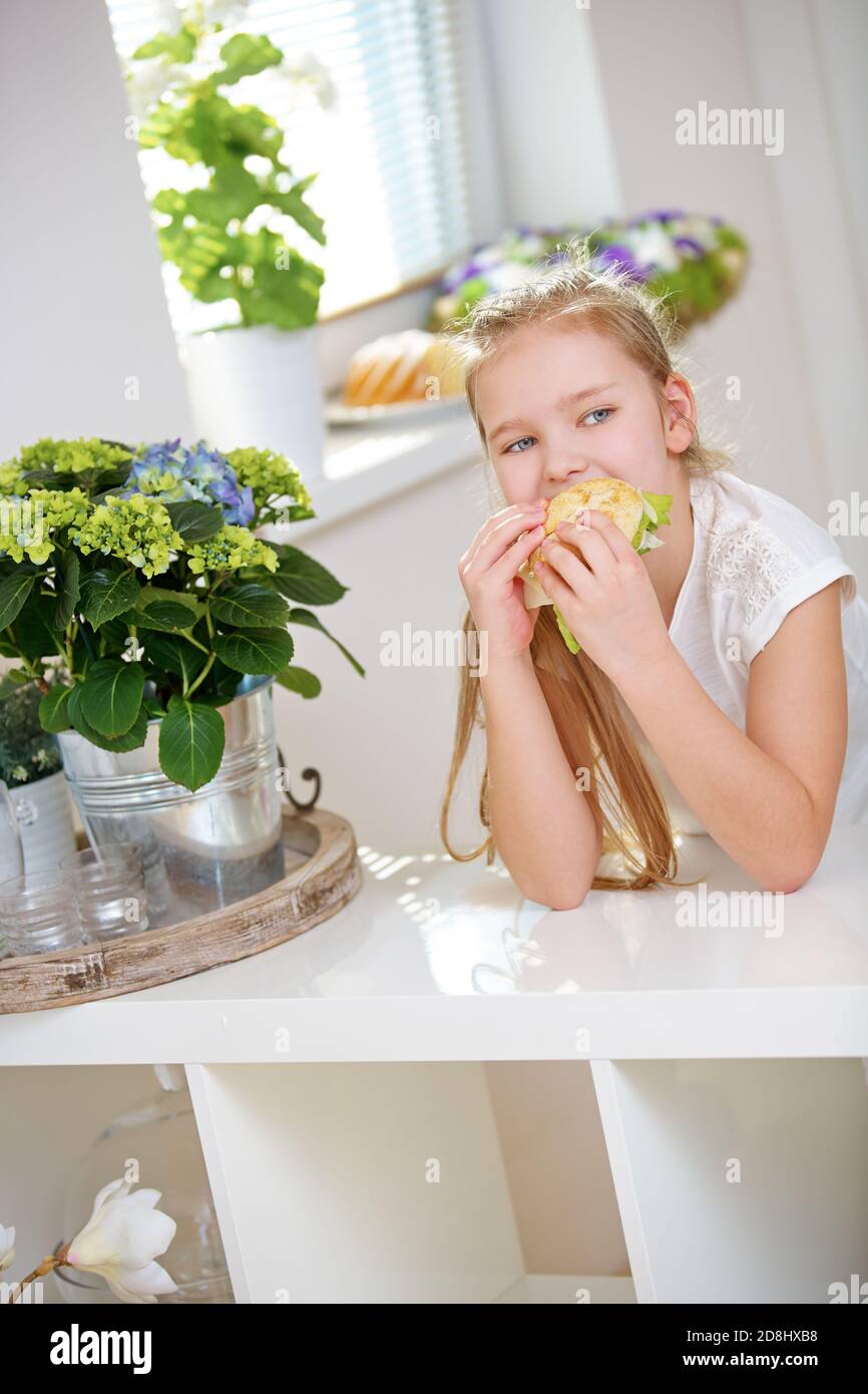L'enfant mange un sandwich dans la cuisine pour le petit-déjeuner Banque D'Images
