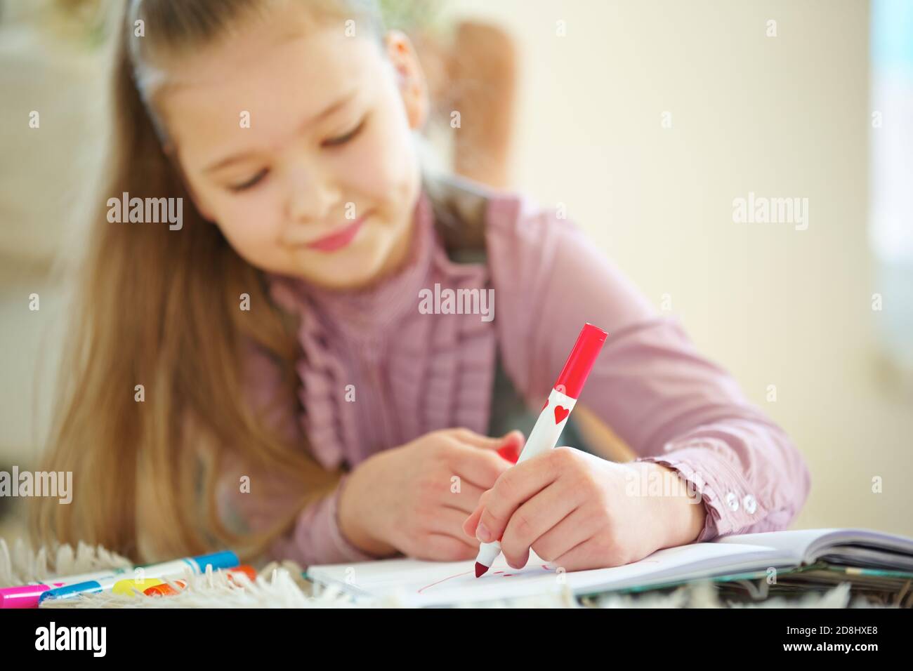 L'enfant tient le stylo rouge à la main pour peindre Banque D'Images