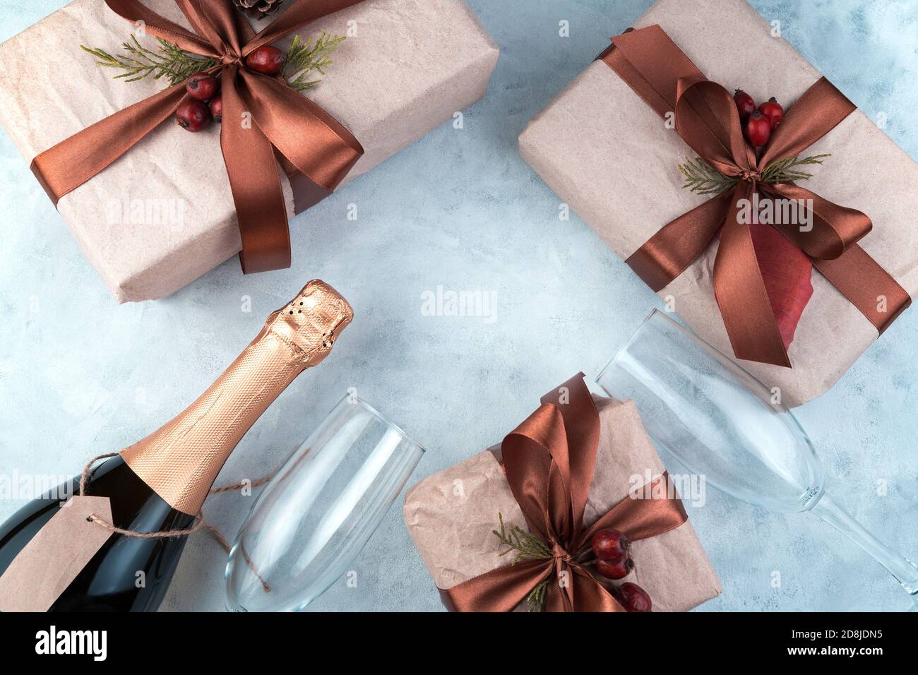 Décor festif avec cadeaux, bouteille de champagne et verres à vin sur fond gris en béton. Banque D'Images