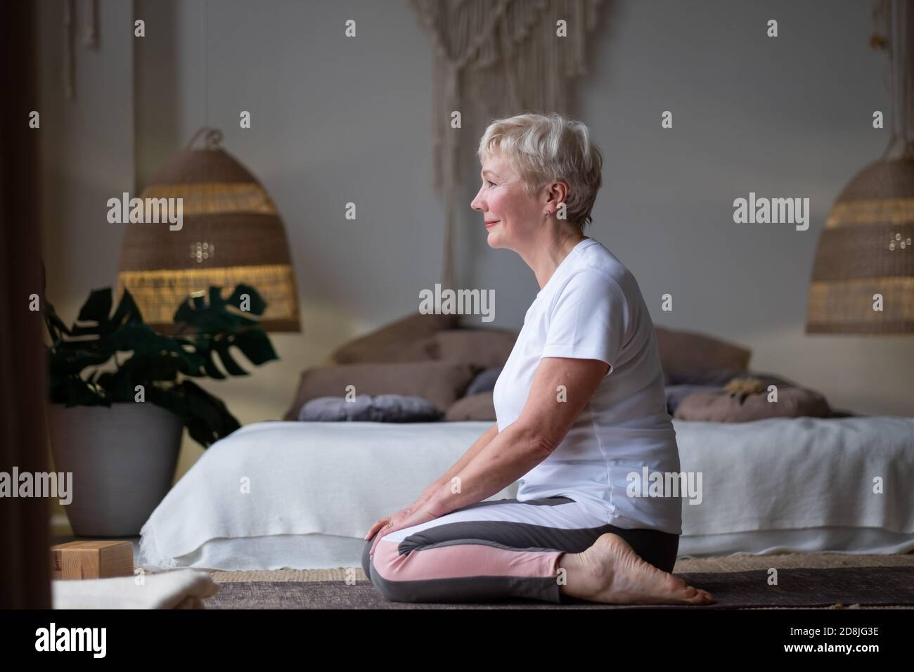 Femme faisant l'exercice de yoga sur le tapis dans Virasana ou Hero pose avec la prière inversée à la maison. Banque D'Images