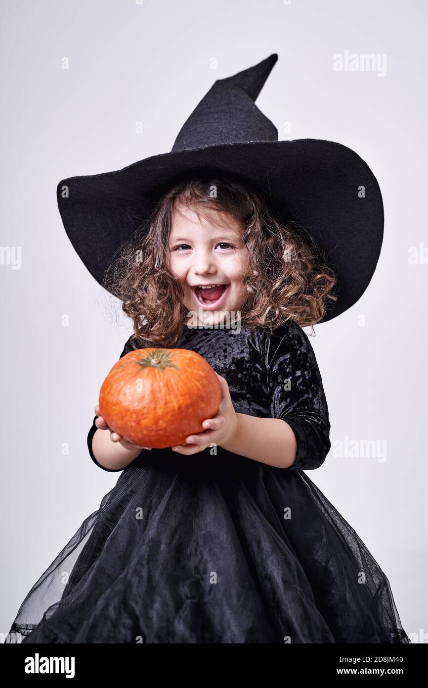 drôle de sorcière fille dans un chapeau avec une citrouille dedans ses mains Banque D'Images